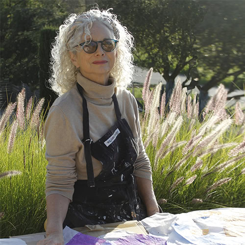 A colorful woman painting outdoors at Ventura Botanical Gardens during Summer Hummerz event.