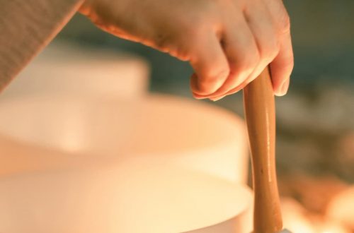 A lush garden scene with a hand playing a singing bowl during a summer solstice event.