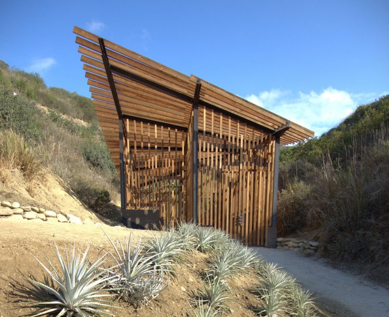 A lush garden entrance with modern wooden structure at Ventura Botanical Gardens.